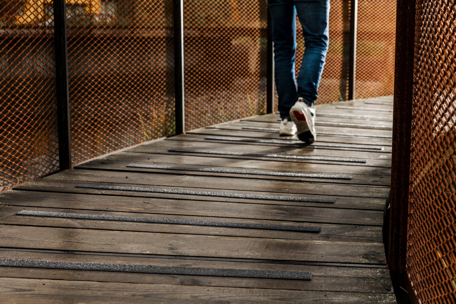 Blöt gångbro i trä med svarta halkskyddslister