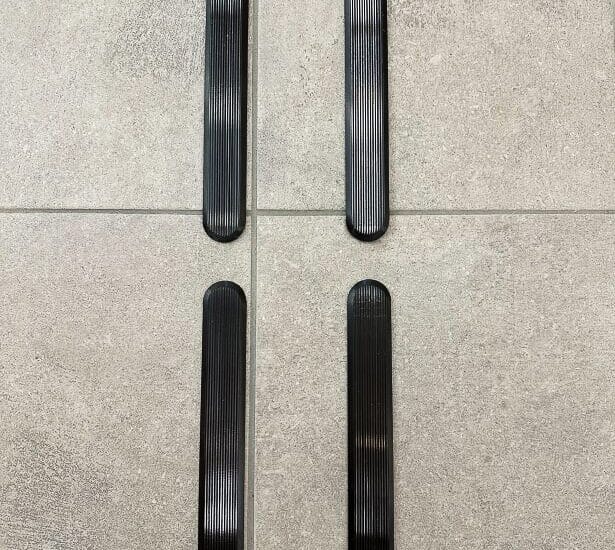 Svarta ledstavar i metall på grått stengolv