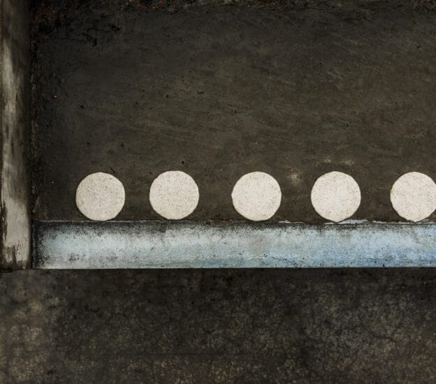 Vita kontrastmarkeringsprickar i termoplast på blöt betongtrappa